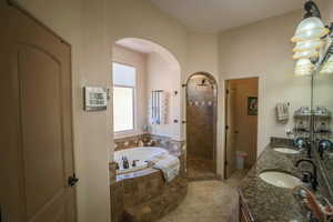 Full bath with double vanity, a shower stall, a garden tub, and light tile patterned flooring