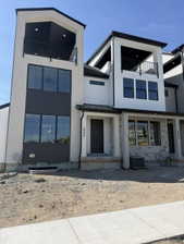 Modern exterior featuring a prominent covered balcony with black railings, white horizontal siding, dark accent panels, and a contrasting black roofline