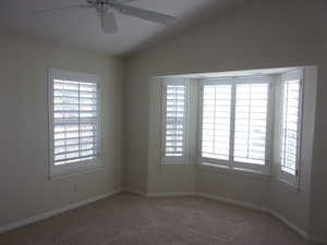 Carpeted empty room featuring a ceiling fan and lofted ceiling
