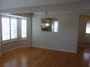 Unfurnished dining area featuring ornamental molding and wood finished floors