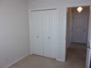 Unfurnished bedroom with light carpet and a closet