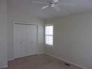 Unfurnished bedroom featuring light carpet, a closet, ceiling fan, and lofted ceiling
