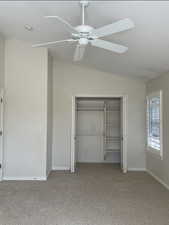 Unfurnished bedroom with vaulted ceiling, a closet, light carpet, and ceiling fan