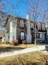 View of front facade featuring a chimney, a front yard, and stone siding