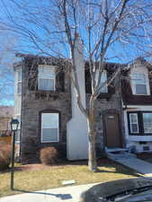 View of front of home featuring stone siding, a chimney, and a front yard