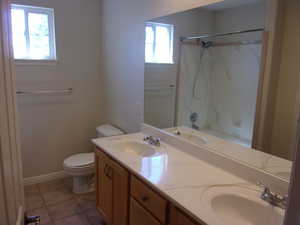 Bathroom featuring double vanity, light tile patterned flooring, and a shower