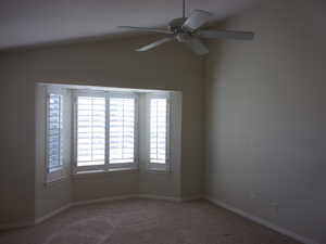 Carpeted spare room with vaulted ceiling and a ceiling fan