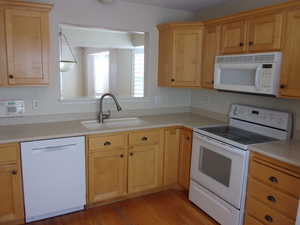 Kitchen with white appliances, light countertops, light wood finish cabinetry, and light wood-type flooring