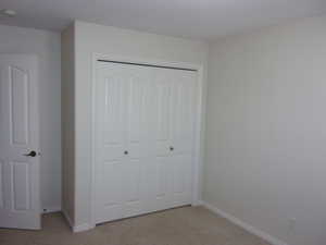 Unfurnished bedroom with a closet and light carpet