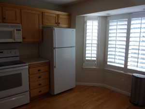 Kitchen featuring white appliances, light wood-style floors, light countertops, and light wood finish cabinetry