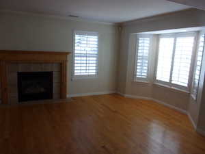 Unfurnished living room featuring ornamental molding, light wood finished floors, and a fireplace