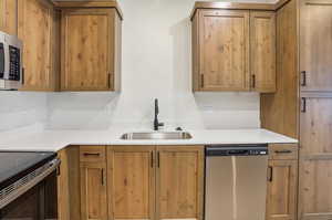 Kitchen with stainless steel appliances, wood finish cabinetry, and light stone counters
