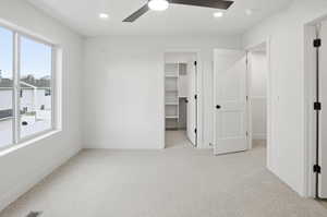 Unfurnished bedroom featuring light carpet, a spacious closet, recessed lighting, and a ceiling fan