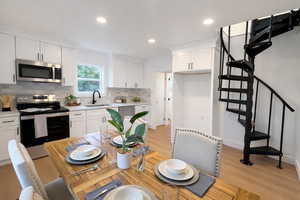 Kitchen featuring stainless steel appliances, white cabinetry, light wood-style flooring, backsplash, and recessed lighting