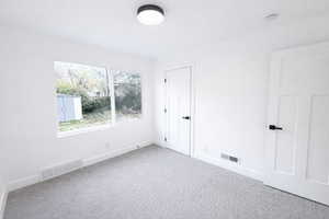 Unfurnished bedroom with light colored carpet and baseboards