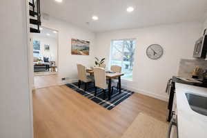 Dining area with light wood-style flooring and recessed lighting