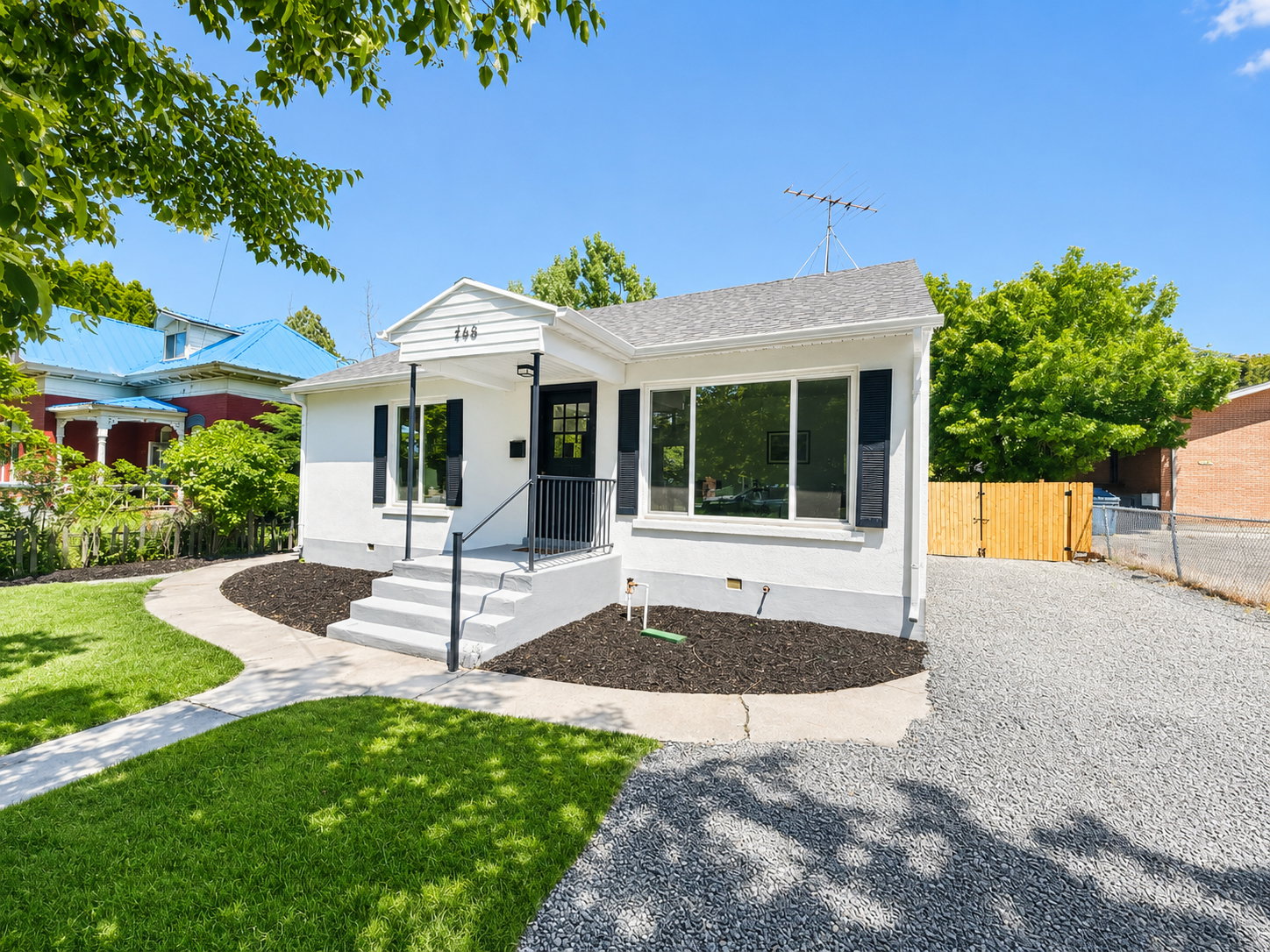 White exterior featuring black window shutters, a front porch with black railing, and a gray shingle roof