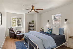 Bedroom with wood finished floors, ceiling fan, and multiple windows