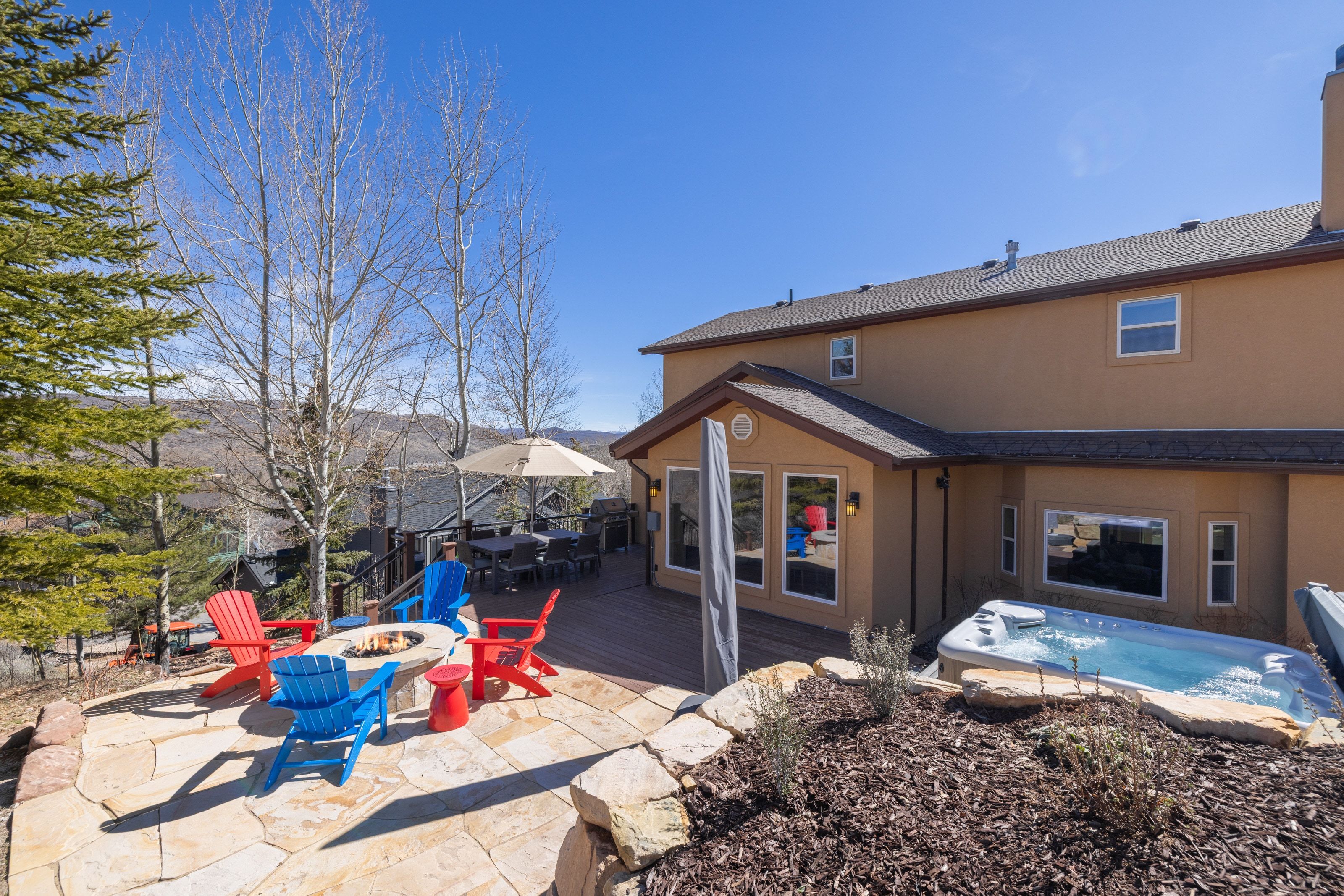 Back of property featuring a fire pit, a hot tub, stucco siding, a patio, and outdoor dining space