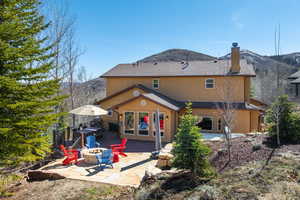 Rear view of house featuring an outdoor fire pit, a chimney, stucco siding, a deck with mountain view, and roof with shingles
