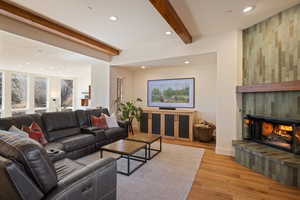 Living area with beamed ceiling, recessed lighting, light wood-style flooring, and a tile fireplace