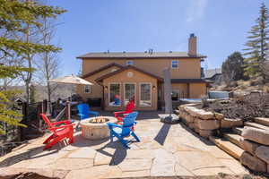 Back of property featuring an outdoor fire pit, a patio, a chimney, and stucco siding