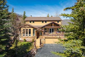 View of front of home featuring a garage, a chimney, driveway, stucco siding, and roof with shingles