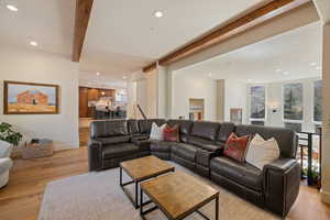 Living room featuring beam ceiling, light wood-type flooring, and recessed lighting