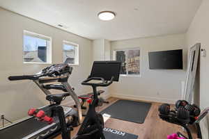 Workout area featuring light wood-style floors and baseboards