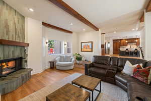 Living area featuring recessed lighting, light wood-type flooring, a tiled fireplace, and beam ceiling
