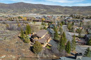 Aerial view of property and surrounding area featuring a mountainous background and nearby suburban area