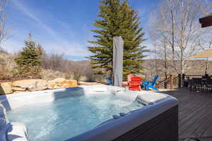 View of pool with outdoor dining space, a deck, and a hot tub