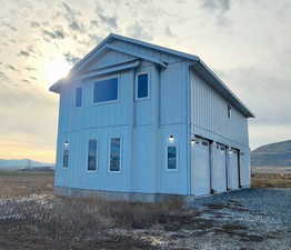 View of side of property featuring a mountain view, driveway, an attached garage, and board and batten siding