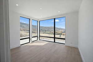 Spare room with light wood-style flooring, a mountain view, and recessed lighting