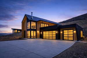 Modern home featuring a garage, concrete driveway, a standing seam roof, and board and batten siding