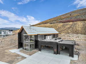 Back of house featuring a mountain view, a sunroom, and driveway
