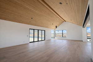 Unfurnished living room with a high wood beamed ceiling, light wood-type flooring, and plenty of natural light