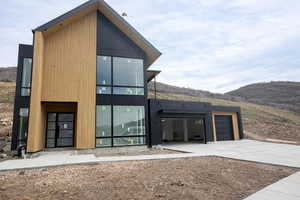 Back of property with an attached garage, concrete driveway, and a mountain view