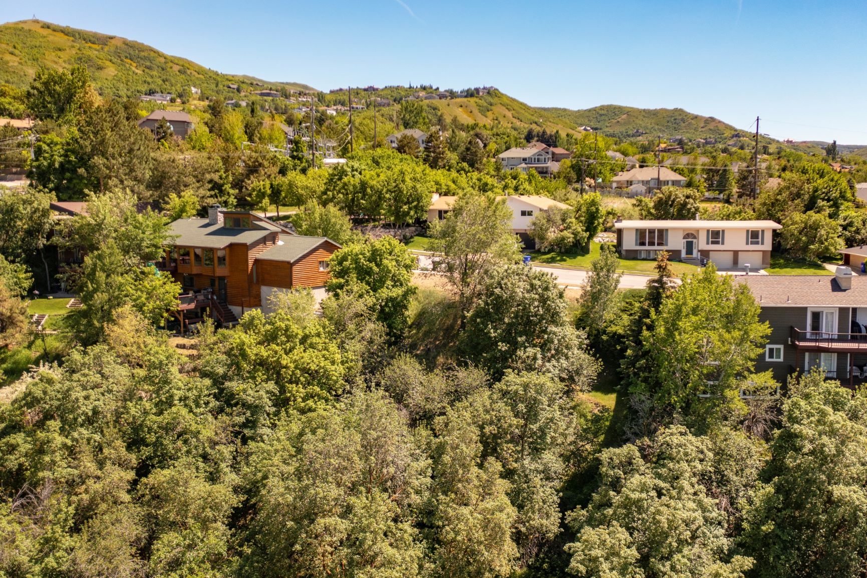Aerial perspective of suburban area with a mountainous background and a tree filled landscape