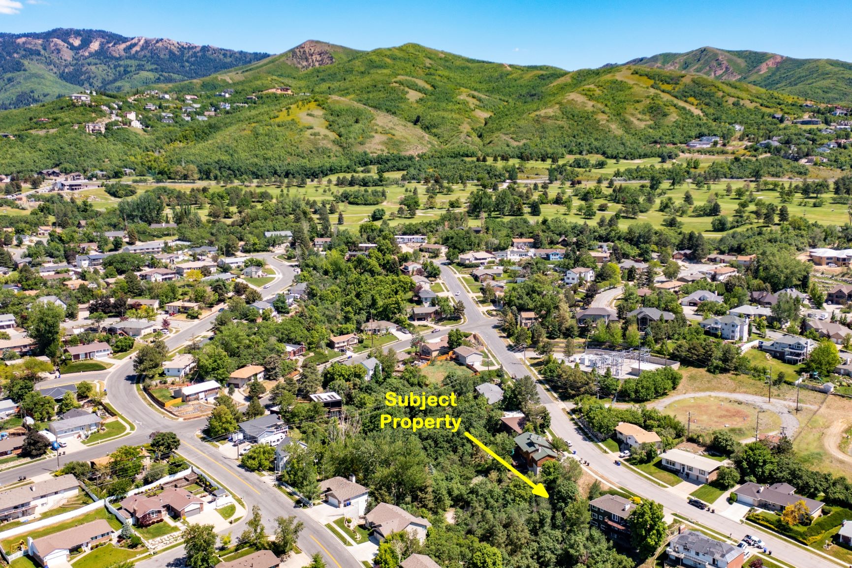 Aerial perspective of suburban area featuring a mountainous background and property parcel outlined