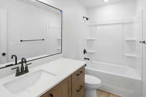 Bathroom with vanity, tub / shower combination, light wood-style floors, and recessed lighting