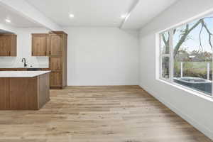 Kitchen featuring wood finish cabinets, light wood-style floors, light stone countertops, and recessed lighting