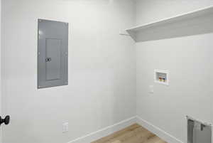 Laundry area featuring light wood-style floors, electric panel, and washer hookup