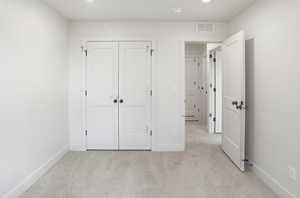 Unfurnished bedroom with light carpet and a closet