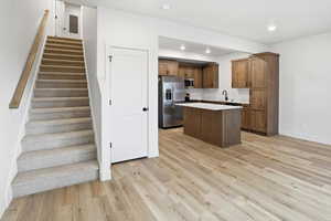 Kitchen featuring a kitchen island, light countertops, light wood finished floors, stainless steel appliances, and wood finish cabinets