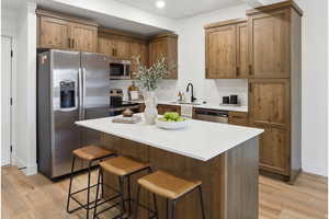 Kitchen featuring stainless steel appliances, a kitchen breakfast bar, a center island, and light wood-style flooring