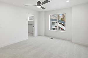 Unfurnished bedroom with a walk in closet, light carpet, a ceiling fan, and recessed lighting