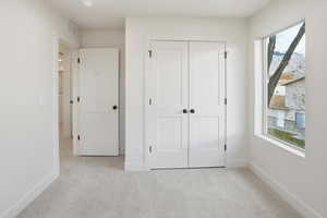 Unfurnished bedroom with light colored carpet and a closet