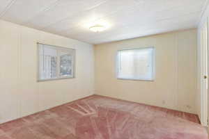 Empty room with a decorative wall, carpet flooring, and a textured ceiling