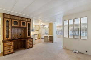 Unfurnished living room featuring light colored carpet, wood walls, a textured ceiling, and ceiling fan